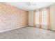 Bedroom featuring a brick wall with large windows and neutral paint colors at 8409 Muirfield Dr, Fuquay Varina, NC 27526
