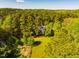 Aerial shot of a charming white house surrounded by lush trees on a large lot, offering privacy and tranquility at 910 Old Orchard Rd, Chapel Hill, NC 27517