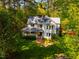 An elevated view showcases a pristine white house nestled amidst a forest, with a brick pathway and lush greenery at 910 Old Orchard Rd, Chapel Hill, NC 27517