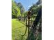 A backyard view highlighting a water faucet with hose connected beside a rustic wooden fence under a sunny blue sky at 910 Old Orchard Rd, Chapel Hill, NC 27517