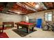 Unfinished basement with exposed ceilings featuring pool table, foosball table and brick walls at 910 Old Orchard Rd, Chapel Hill, NC 27517
