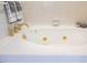 Close up of a pristine white soaking tub with tile surround and gold fixtures at 910 Old Orchard Rd, Chapel Hill, NC 27517