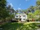 Charming two-story white home with a welcoming front porch, surrounded by mature trees and lush landscaping at 910 Old Orchard Rd, Chapel Hill, NC 27517