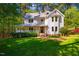 A well-maintained two-story home featuring a large porch, mature trees, and green lawn creating a serene setting at 910 Old Orchard Rd, Chapel Hill, NC 27517