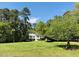 Beautiful two-story white home with a metal roof surrounded by mature trees and a sprawling green lawn at 910 Old Orchard Rd, Chapel Hill, NC 27517