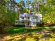 Beautiful two-story home boasts a metal roof, covered front porch, and well-manicured lawn, set amongst mature trees at 910 Old Orchard Rd, Chapel Hill, NC 27517