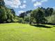 Spacious green lawn with mature trees, landscaping, and a rustic fence creating a serene outdoor retreat at 910 Old Orchard Rd, Chapel Hill, NC 27517