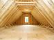 Unfinished attic space features a framed window, wooden beams, and tongue and groove subflooring at 921 Lily Claire Ln, Fuquay Varina, NC 27526