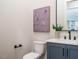Powder room with blue vanity, white countertop, and a decorative mirror at 921 Lily Claire Ln, Fuquay Varina, NC 27526