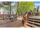 Backyard with an outdoor dining area and grill, steps to a wooden deck, and mature trees at 9332 Leslieshire Dr, Raleigh, NC 27615