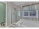 Well-lit bathroom featuring a walk-in shower, soaking tub, and window with privacy curtains at 9332 Leslieshire Dr, Raleigh, NC 27615