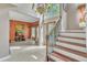 Sunlit foyer with tile flooring, a staircase featuring iron railings, and a view of a living area with decorative wallpaper at 9332 Leslieshire Dr, Raleigh, NC 27615