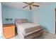 Bright bedroom with a ceiling fan, light blue walls, rustic wooden bed frame, and a box on a desk at 10 Gray Bass Ct, Zebulon, NC 27597