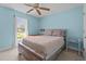 Bright bedroom featuring light blue walls, a ceiling fan, a rustic wooden bed frame, and large windows at 10 Gray Bass Ct, Zebulon, NC 27597
