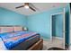 Bright bedroom featuring a ceiling fan, wooden bedframe with blue accent blanket, and a door leading to another room at 10 Gray Bass Ct, Zebulon, NC 27597