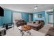 Bright living room with blue walls, neutral carpet, large windows, and comfortable seating at 10 Gray Bass Ct, Zebulon, NC 27597