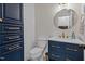 Stylish bathroom with navy blue vanity, decorative mirror, and patterned wallpaper at 104 Chuckwagon Dr, Louisburg, NC 27549