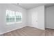 Neutral bedroom featuring plush carpeting, a large window, and a white door at 11470 International Dr, Middlesex, NC 27557