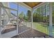 Angle from inside screened-in porch showcasing wood floors, ceiling, and an adjoining deck with backyard and wooded views at 129 Camille Cir, Youngsville, NC 27596