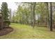 Lush backyard area with mature trees and views of wooden deck with grill at 1335 Saint Andrews Dr, Mebane, NC 27302