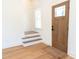Bright entryway with light hardwood floors, small stairs, and front door at 1394 Delma Grimes Rd, Coats, NC 27521