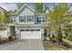 Beautiful light blue townhouse with a two-car garage has manicured landscaping and a walkway at 1614 Brussels Drive Dr, Apex, NC 27502