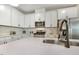 Close up of a well-lit kitchen featuring a stainless steel sink, appliances, and white cabinets at 1614 Brussels Drive Dr, Apex, NC 27502