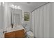 Bright bathroom with a wood vanity, framed art, and a shower-tub combo with white shower curtain at 1640 Legendary Ln, Morrisville, NC 27560