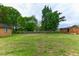 Expansive green backyard with mature trees, fencing, and a glimpse of the home's exterior at 1744 Prince Edward Dr, Elon, NC 27244