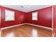 Red bedroom with hardwood floors and two windows at 1744 Prince Edward Dr, Elon, NC 27244