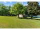 Large, grassy backyard with mature trees, shed, and partially visible play set at 20 Sanders Rd, Benson, NC 27504
