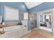 Bright bathroom featuring a glass-enclosed shower, soaking tub, and blue walls at 2000 Silverleaf Dr, Youngsville, NC 27596