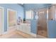 Bright bathroom featuring a glass-enclosed shower, soaking tub, and blue walls at 2000 Silverleaf Dr, Youngsville, NC 27596