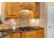 Close up of kitchen including wood cabinets, granite counters, and a tile backsplash above the stove at 2000 Silverleaf Dr, Youngsville, NC 27596