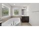 Bright bathroom featuring a modern soaking tub, dark vanity and window providing natural light at 204 Concordia Woods Dr, Morrisville, NC 27560