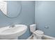 Half bathroom features blue walls, a white sink, and a toilet at 2214 Bayswater Dr, Creedmoor, NC 27522