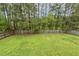 Large grassy backyard enclosed by a wooden fence and lined with mature trees provides a private outdoor space at 225 Lodestone Dr, Durham, NC 27703