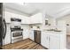 Well-lit kitchen with stainless steel appliances, white cabinets, and wood-look flooring at 225 Lodestone Dr, Durham, NC 27703