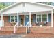 Inviting front porch with brick steps, white railings, and blue shutters at 2314 Clements Dr, Durham, NC 27704