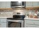 Close-up of stainless steel oven and microwave with gray tiled backsplash at 2314 Clements Dr, Durham, NC 27704