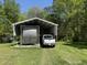 Large carport with a camper and truck parked beneath it on a well-maintained lawn at 2385 Olde Spring Ct, Graham, NC 27253