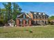 Traditional brick home featuring a manicured lawn and three-car garage surrounded by beautiful greenery at 3001 Greystone Dr, Rocky Mount, NC 27804