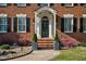 Charming front entrance with a classic black door, brick steps, stone landscaping, and lush greenery at 3001 Greystone Dr, Rocky Mount, NC 27804