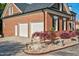 Red brick garage with two white doors and manicured landscaping featuring a maple tree and decorative rocks at 3001 Greystone Dr, Rocky Mount, NC 27804