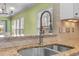 Close-up of a stainless steel sink, granite countertop, and a tiled backsplash in a brightly lit kitchen at 320 Easton Grey Loop, Cary, NC 27519