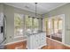 Kitchen island with stainless steel top, white cabinets, and modern lighting, adjacent to sliding glass doors at 320 Easton Grey Loop, Cary, NC 27519