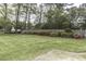 Large backyard featuring a green lawn, colorful landscaping, mature trees, and a wooden fence at 3609 Hawthorne Rd, Rocky Mount, NC 27804
