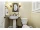 Charming powder room featuring a pedestal sink, toilet and decorative mirror at 3609 Hawthorne Rd, Rocky Mount, NC 27804