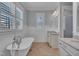 Bright bathroom with a clawfoot tub, wainscoting, granite vanity, and window shutters at 39 Drayton St, Clayton, NC 27527