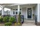 Inviting front porch with black metal railing, wicker chairs and a decorative wreath on the front door at 408 Torwood Cir, Apex, NC 27523